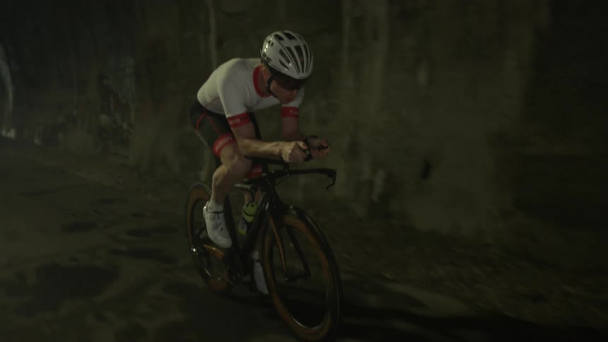 A man is riding a bicycle through a tunnel in daylight