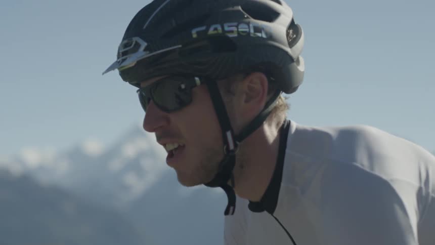 A man is riding a bicycle in a mountain landscape on a sunny day