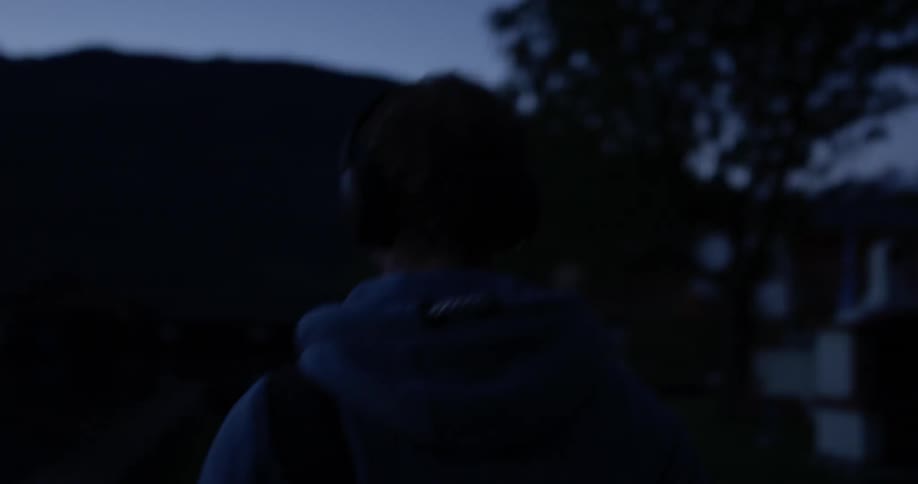 A person wearing headphones is walking at dawn