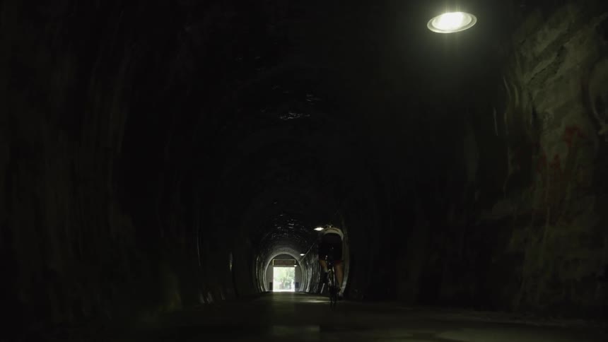 A person rides their bicycle to the tunnel exit