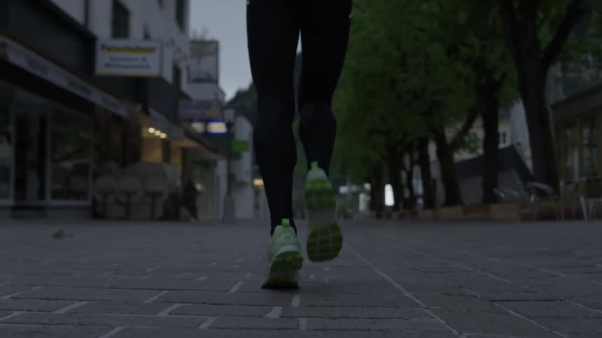 A woman jogs down a city sidewalk at sunset