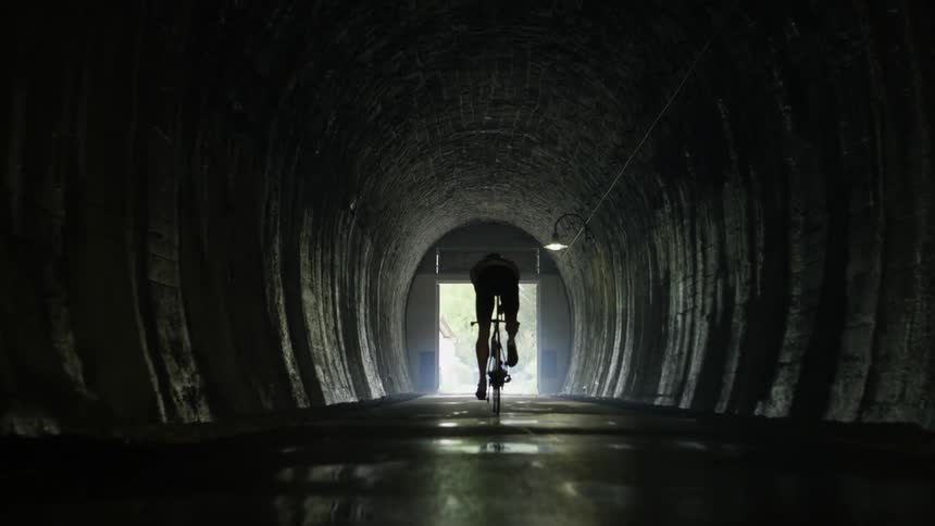 Person rides a bike through a tunnel