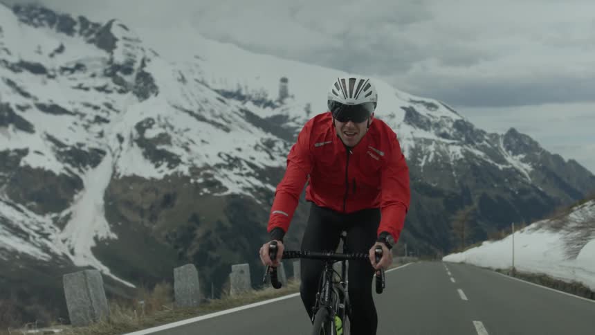 A man is riding a bicycle on a mountain road on a cloudy winter day