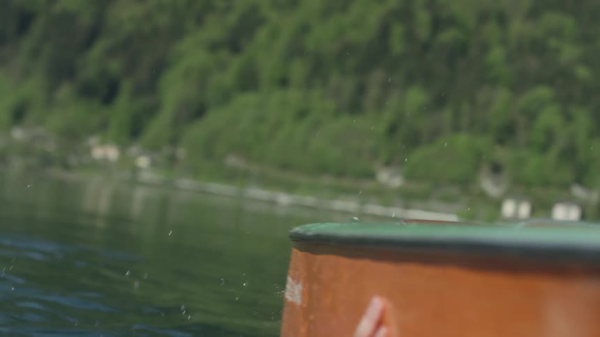 Man swimming in a river grabs hold of a boat