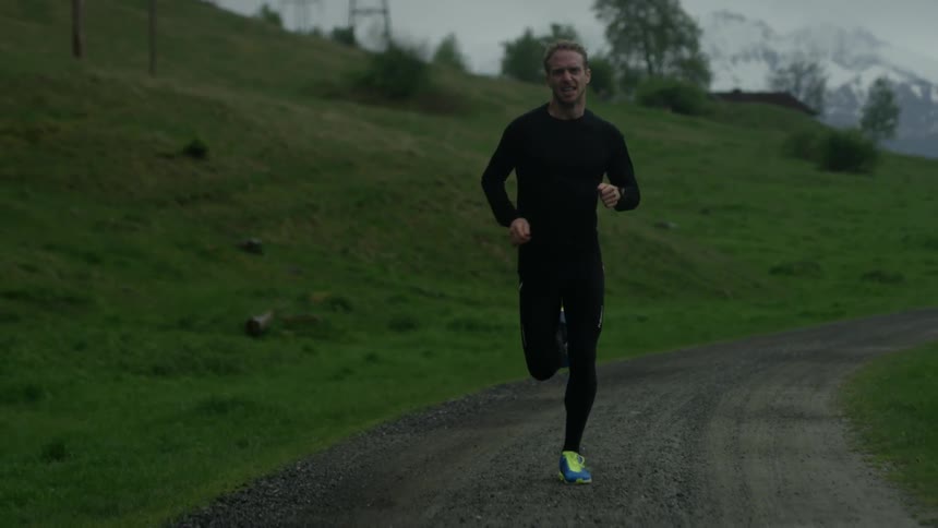 A man is jogging on the trail on a cloudy day