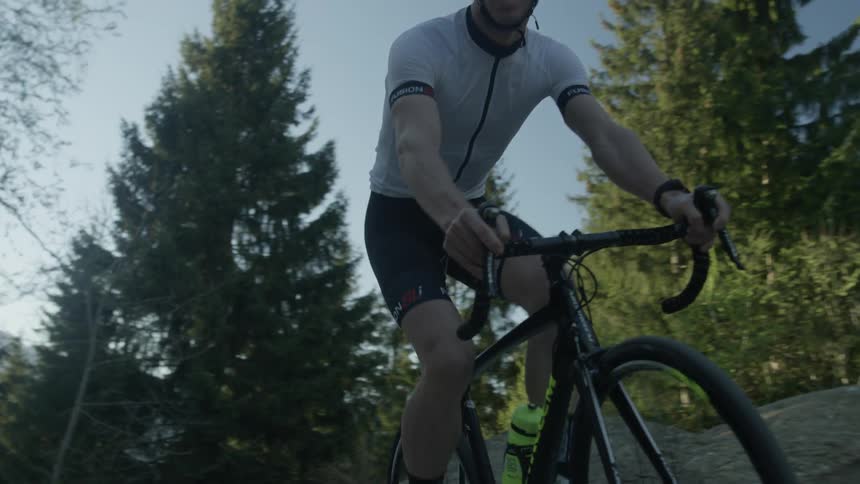 A man is riding a bicycle on a mountain road on a sunny day