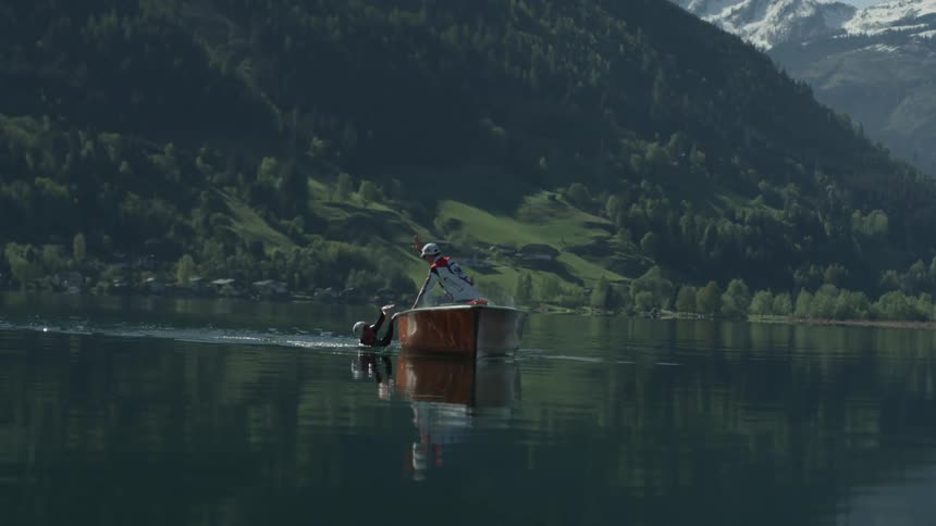 A man in the water reaches up to give a high five to the other man in the boat