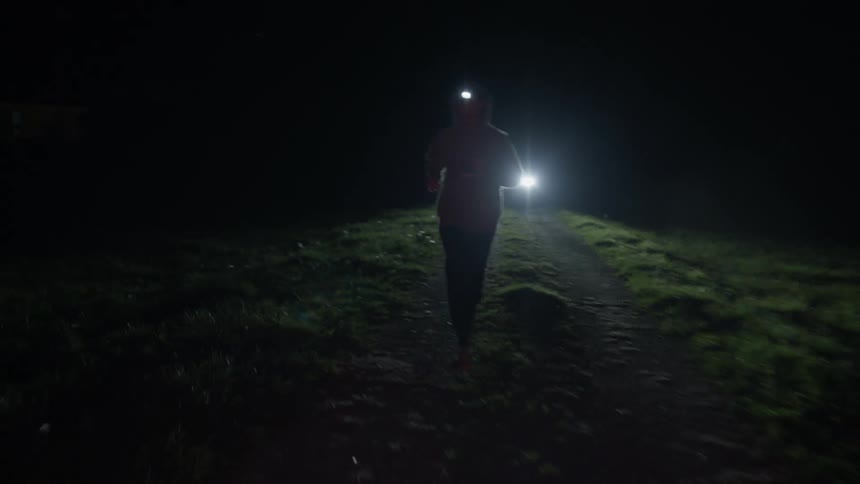 A person is running at night with a car behind