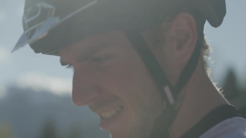 A bicyclist stands outside as water drips from his helmet