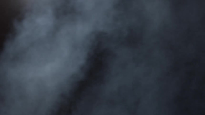 Smoke is blowing across a landscape in the dark