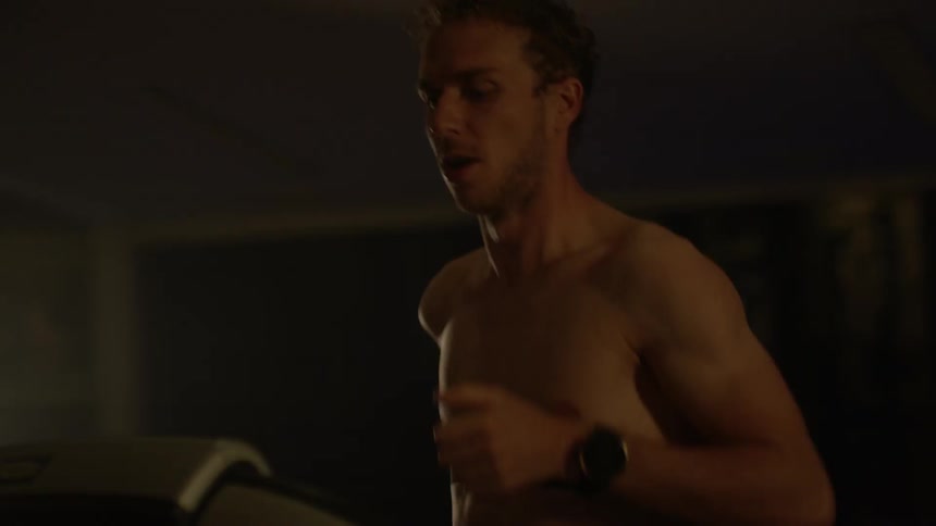 A man is jogging on a treadmill inside in daylight