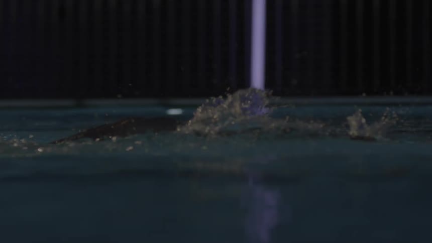 A person wearing a swim cap swims in a pool