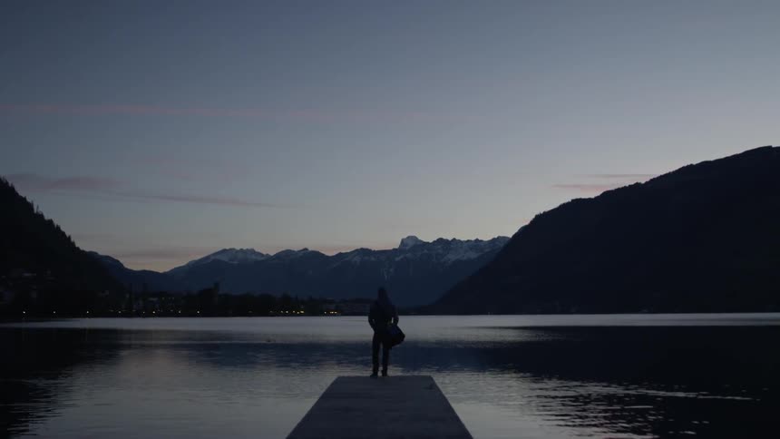 A person is standing on the edge of the pier looking at the lake