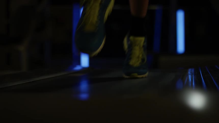 A person running on a treadmill in a dark room