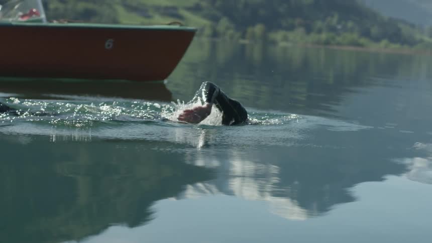 A man swims alongside a boat in a lake