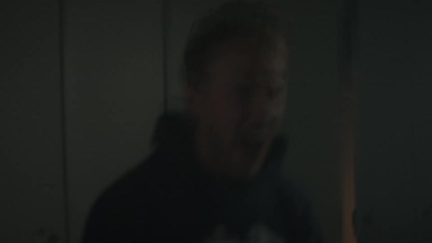 A man is standing in the dark room screaming