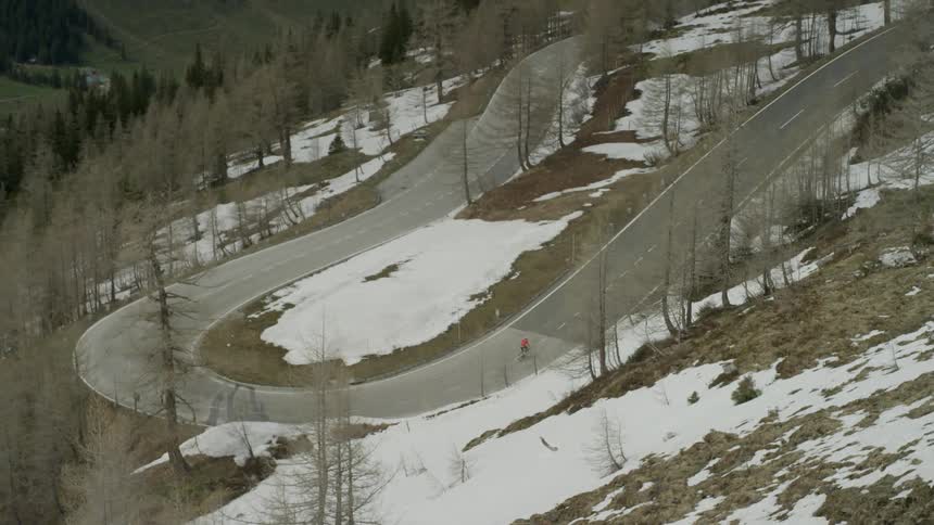 A skateboarder rides on a mountain road
