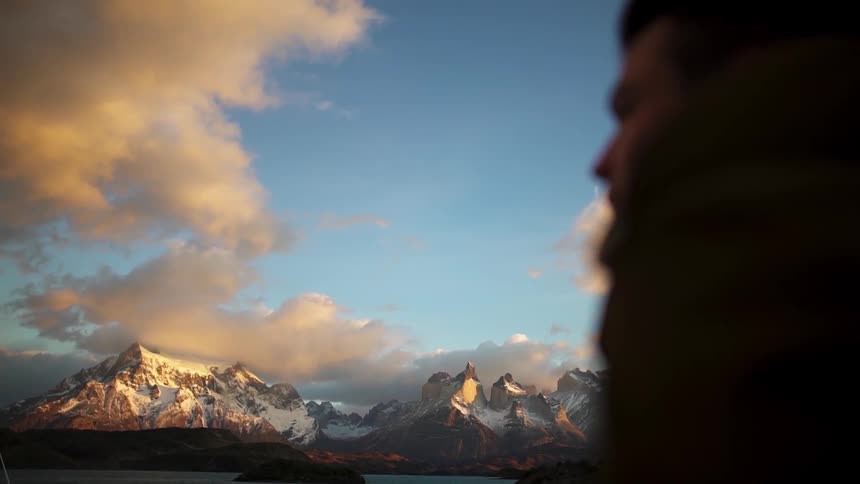 A man walks over to view a mountain ahead