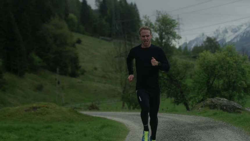 A man is jogging on a dirt trail under cloudy skies