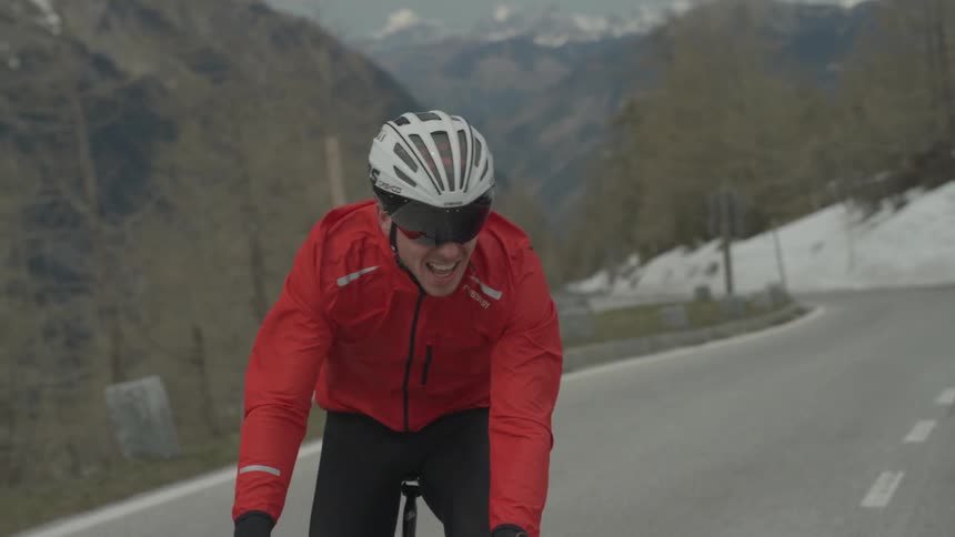 A man rides a bicycle up a mountain road on a winter day