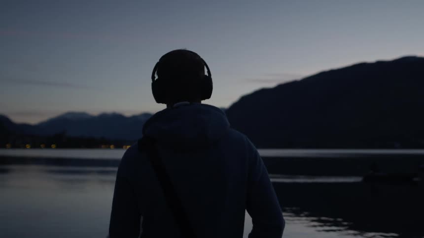 A man walks next to a mountain lake at dusk