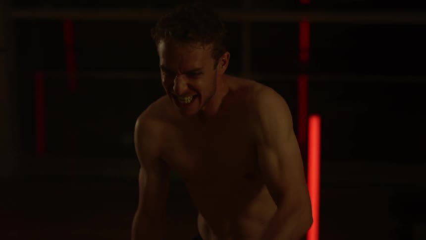 A man is using ropes as he exercises inside at night