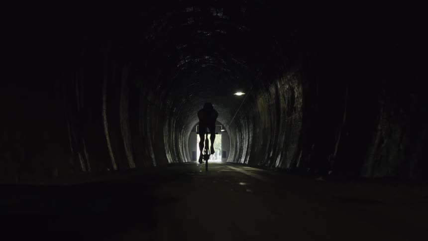 Someone is riding a bike through a dark tunnel