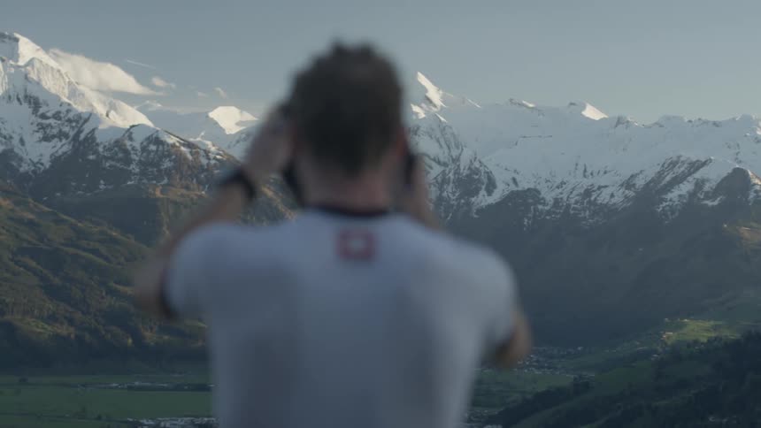 A bicyclist removes his helmet while looking at the mountain view