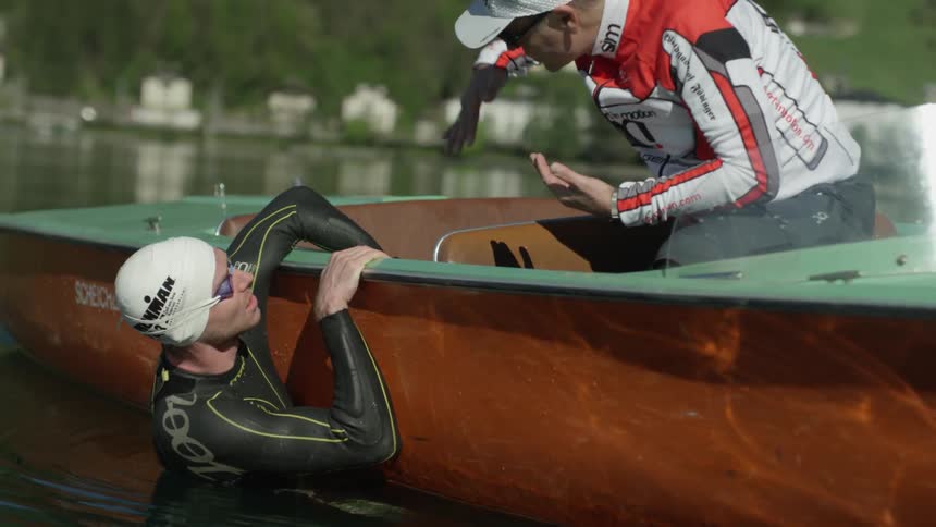 A man swims alongside a boat in a lake