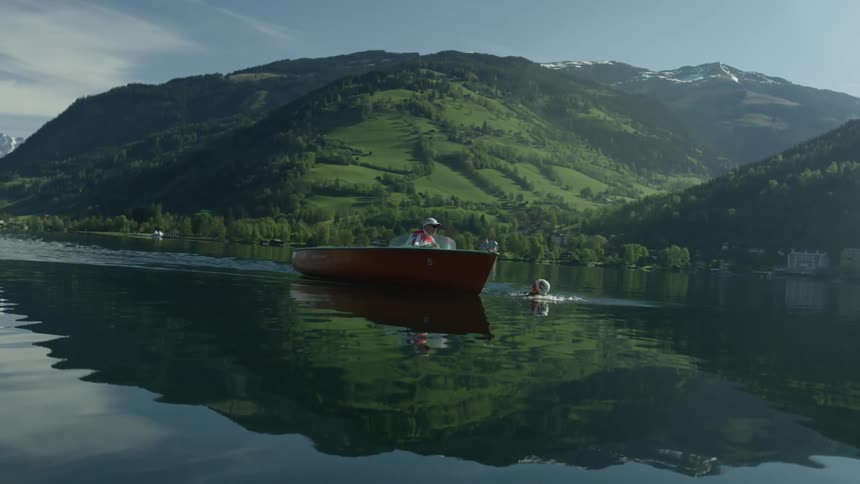 A man swims alongside a boat in a lake