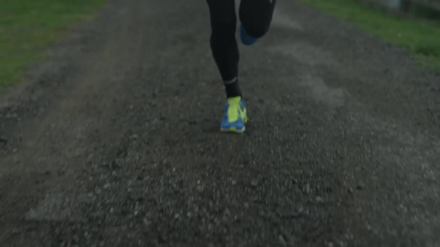 A man is jogging on a dirt trail under cloudy skies