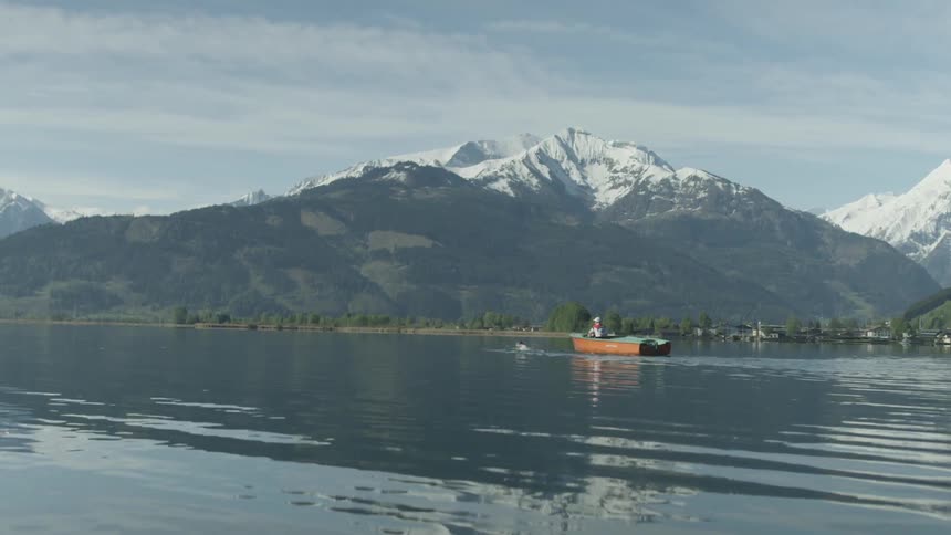 Person swims alongside small orange canoe in a river