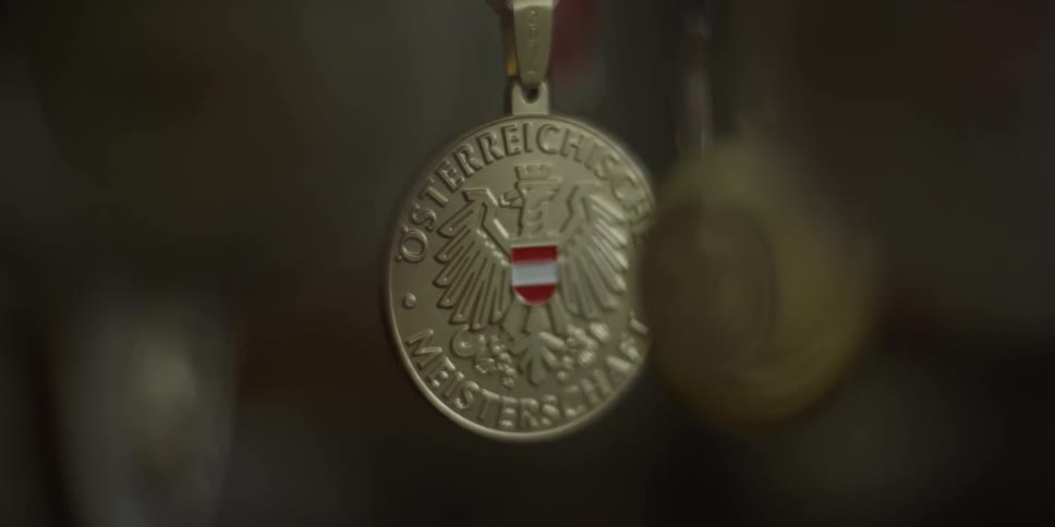 A gold metal with a bird engraved on it is hanging