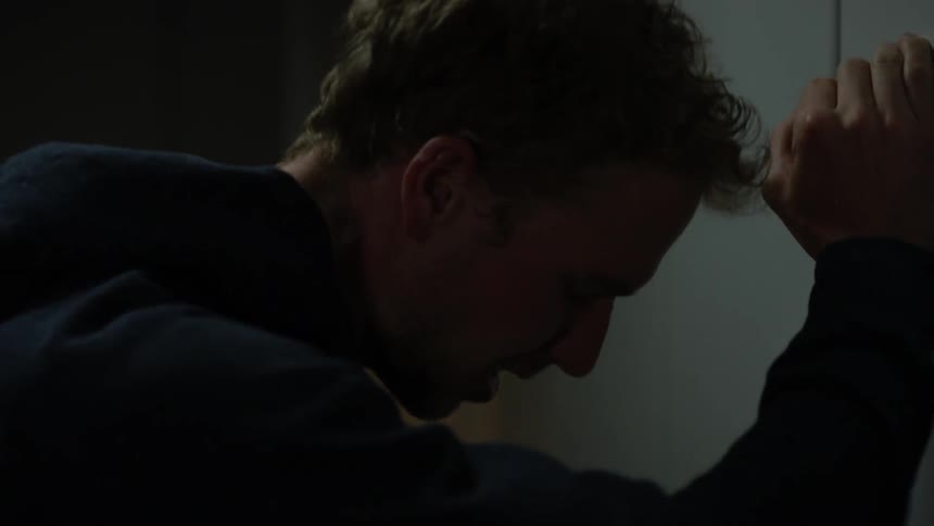 The man pushes the door closed and leans against it