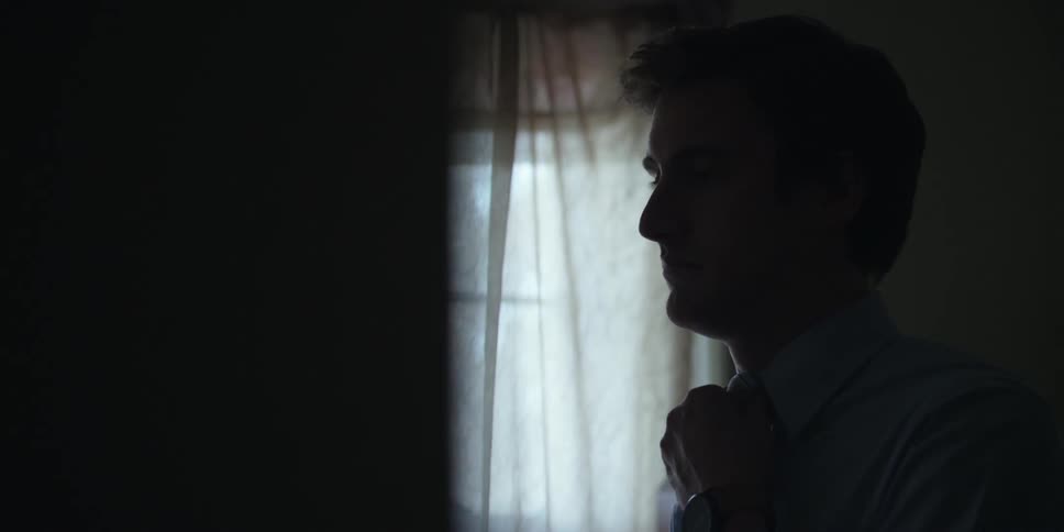 Man adjusting his tie in a room
