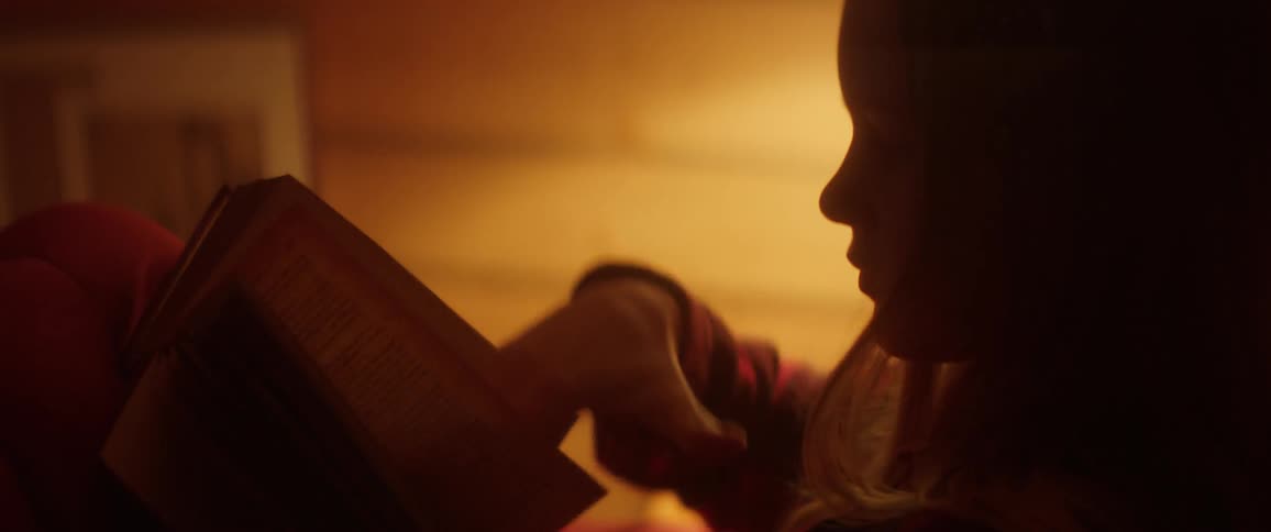 A girl is reading a book in her bedroom