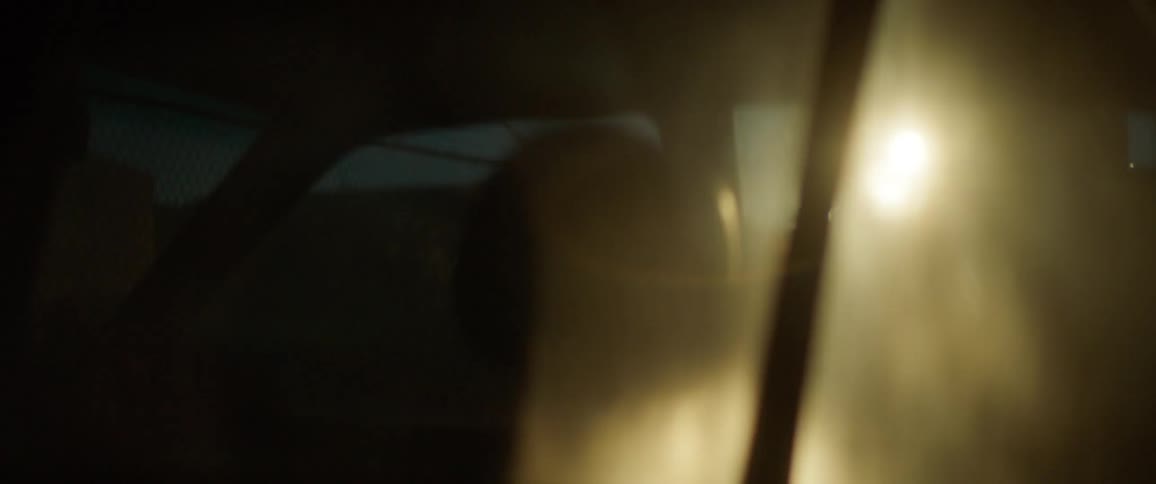 A woman shines a flashlight into a parked car at night
