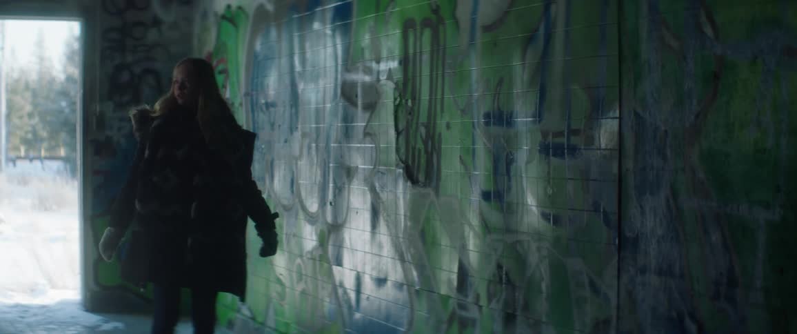 A young woman walks into a graffiti filled structure