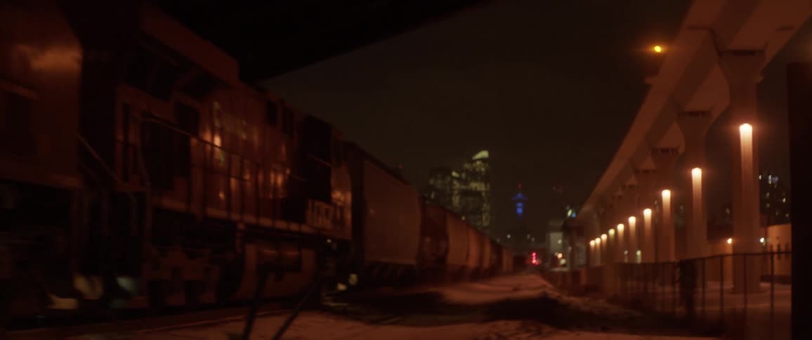 A train travels under an overpass at night