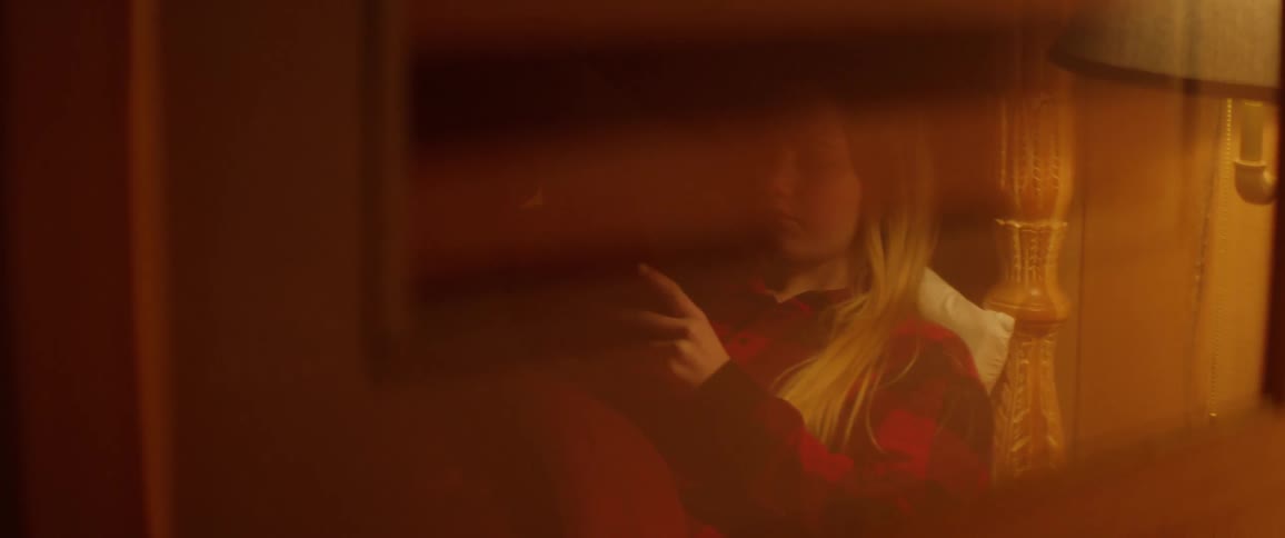 A girl is laying in bed reading a book