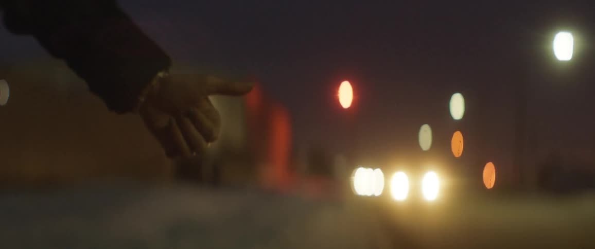 Cars drive by a hitchhiker at night