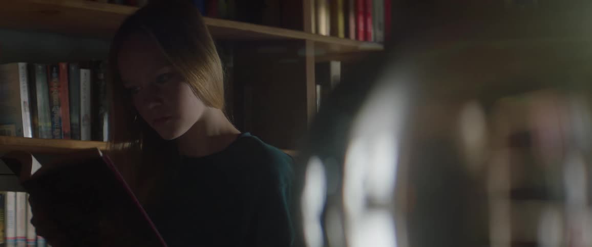 A woman grabs a book from a bookcase