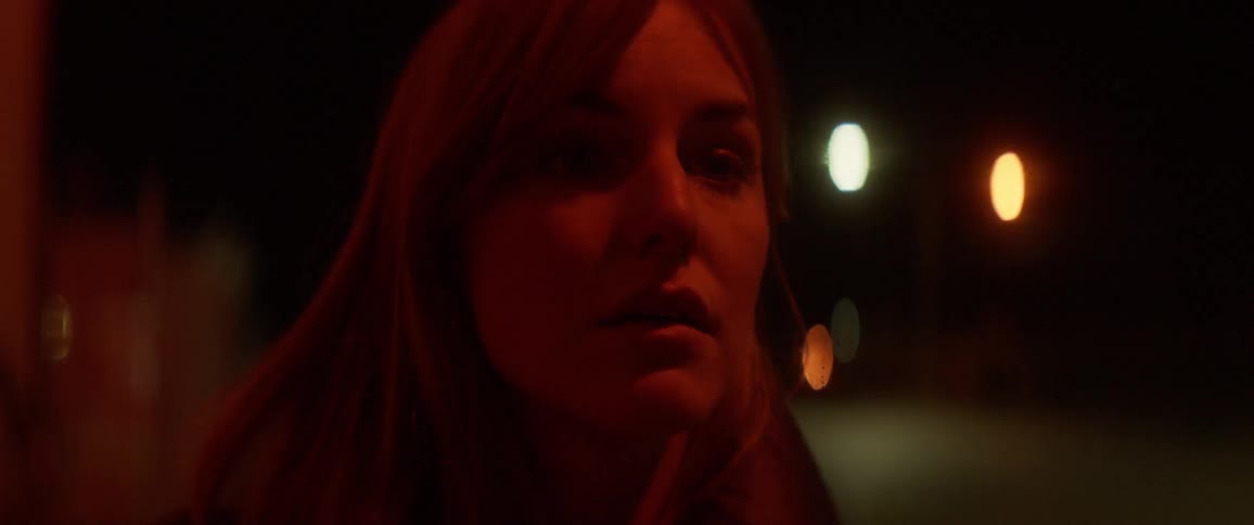 A woman is staring forward at night