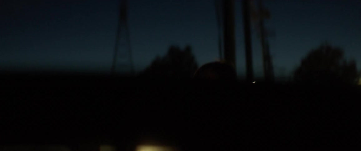 A woman shines a flashlight into a car at night