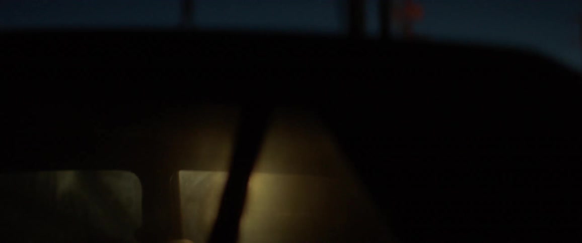 A woman is using a flashlight to peer into an empty vehicle at night