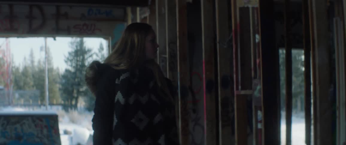 A girl looks around at the graffiti on the studs and walls of a building