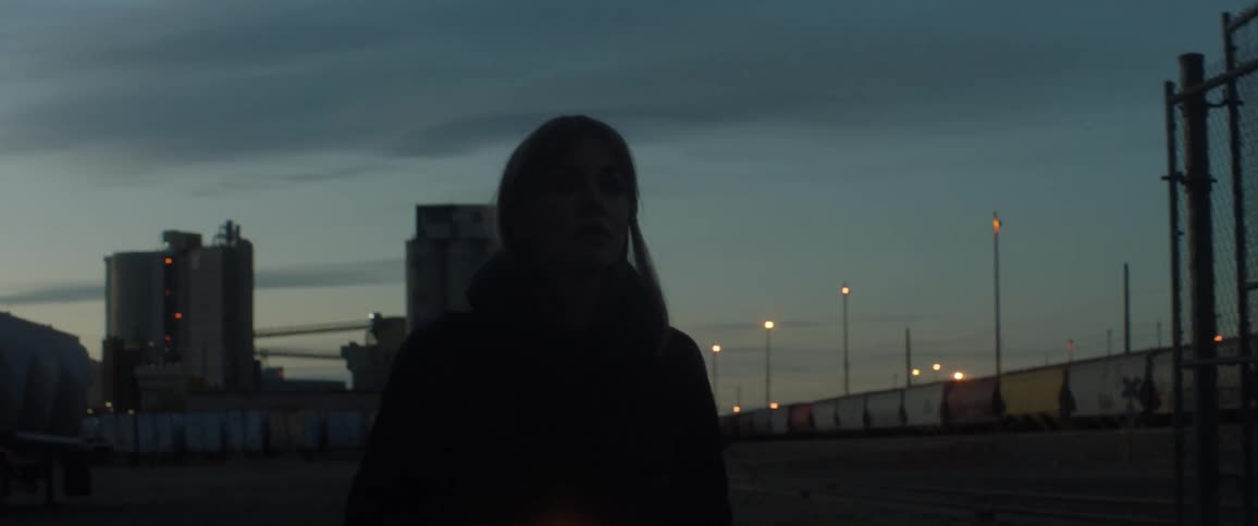 A woman is searching around at dawn with a flashlight