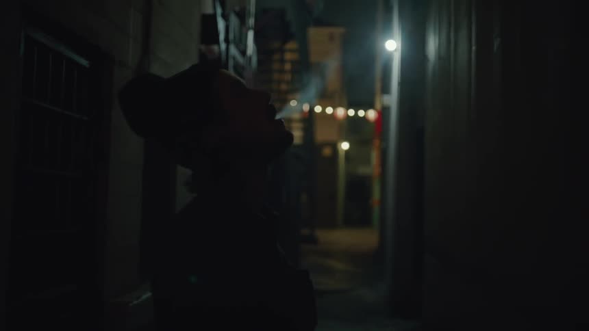 A person is smoking in the dark alley