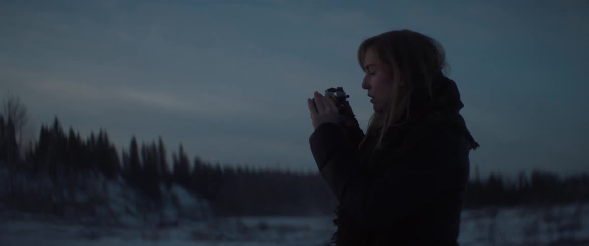 A woman takes photographs outside in the snow