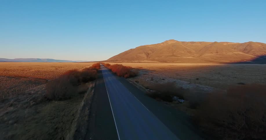 A car is traveling down the small road near the desert